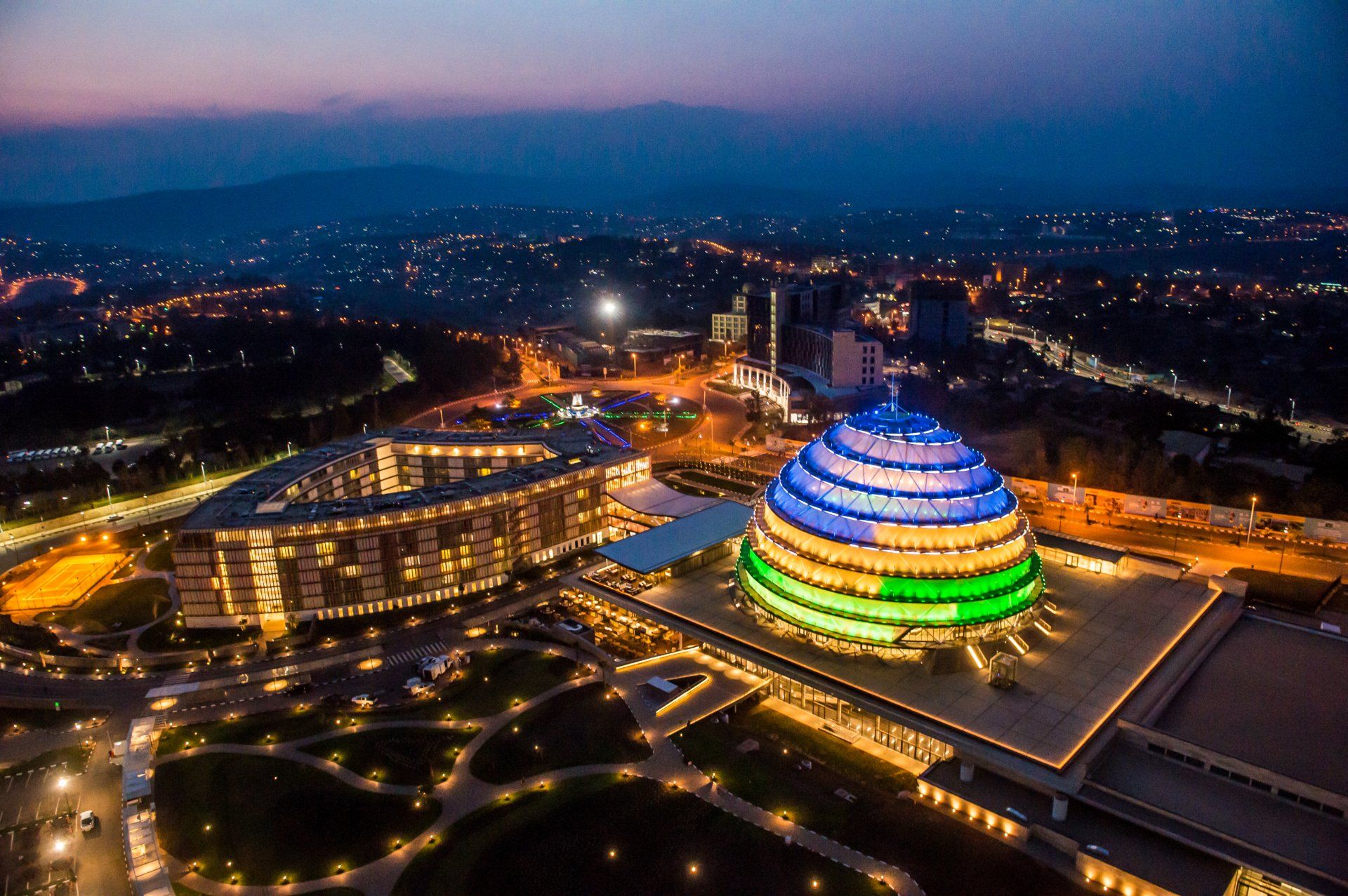 Kigali Convention Centre lit at night with the city beyond