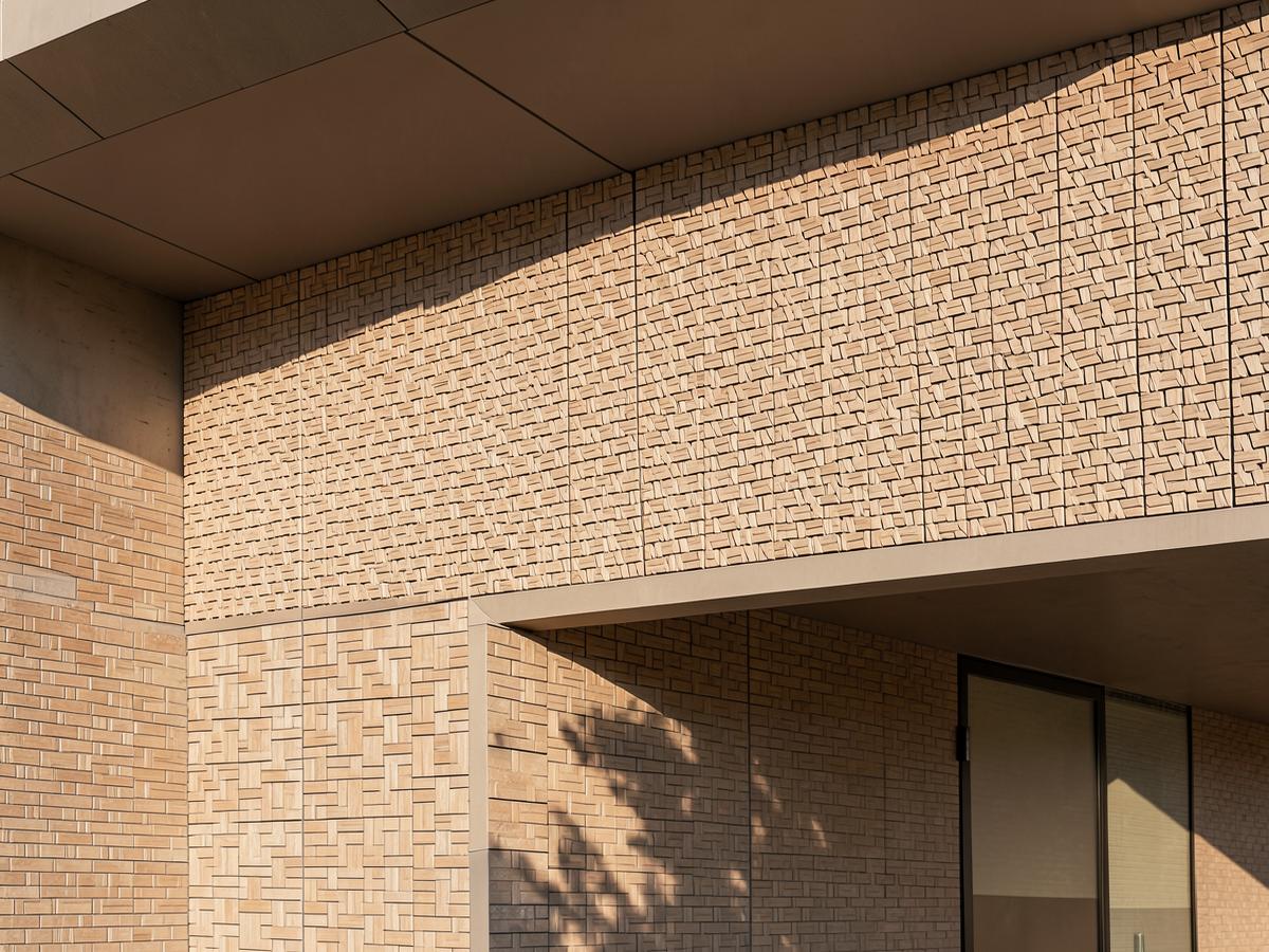 Close view of a patterned brick facade in raking sunlight